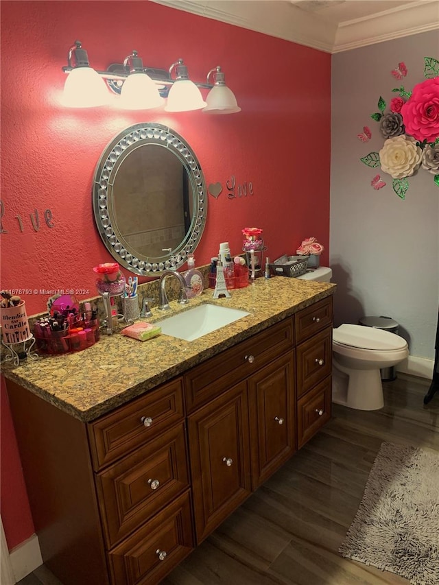 bathroom with toilet, vanity, wood-type flooring, and ornamental molding