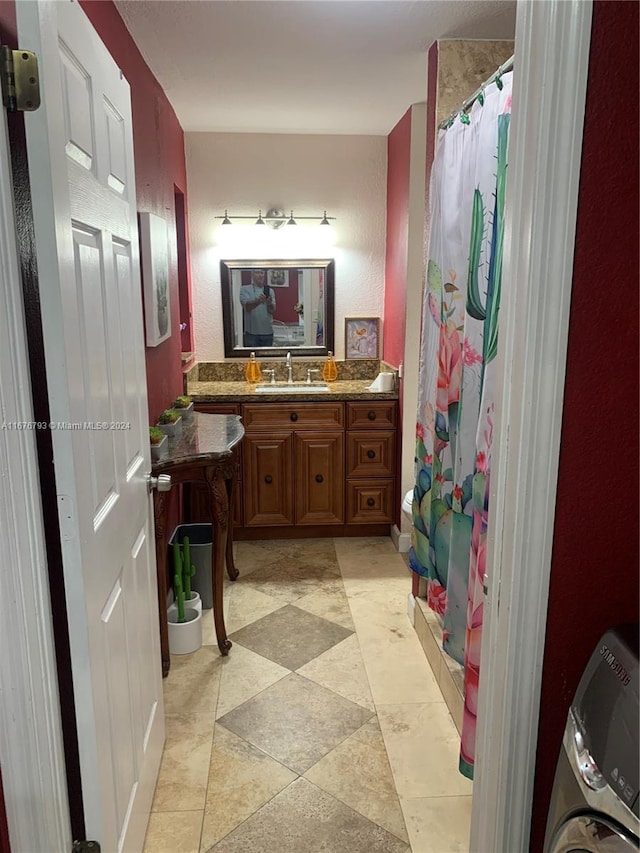 bathroom featuring washer / dryer, vanity, and walk in shower