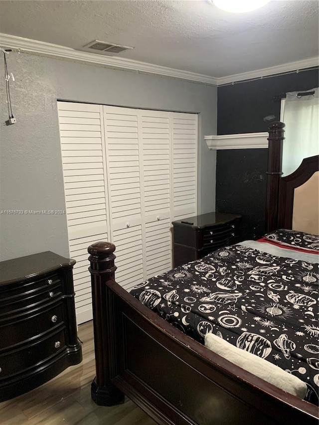 bedroom with crown molding, a closet, wood-type flooring, and a textured ceiling