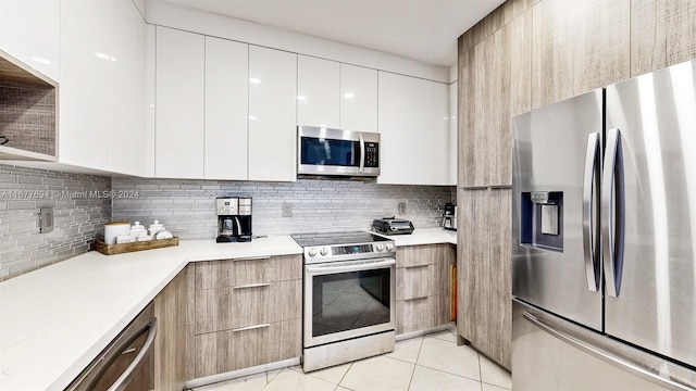 kitchen with backsplash, stainless steel appliances, light tile patterned floors, and white cabinets