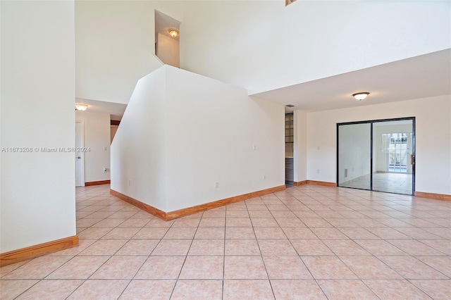 unfurnished room featuring a towering ceiling and light tile patterned flooring