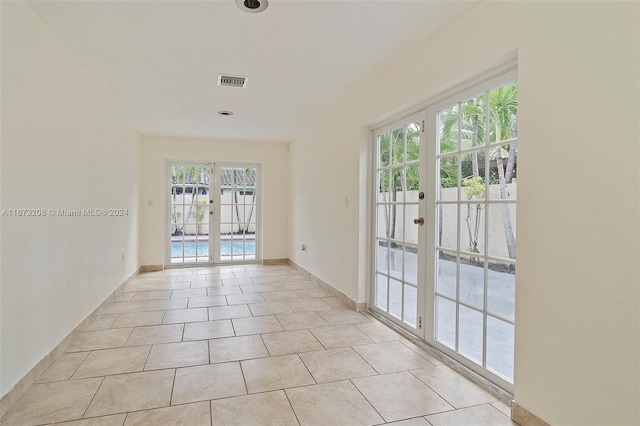 tiled empty room featuring french doors