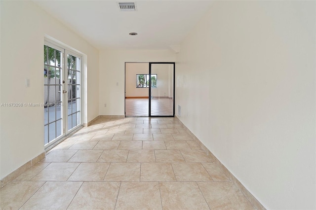 unfurnished room featuring french doors, a healthy amount of sunlight, and light tile patterned floors