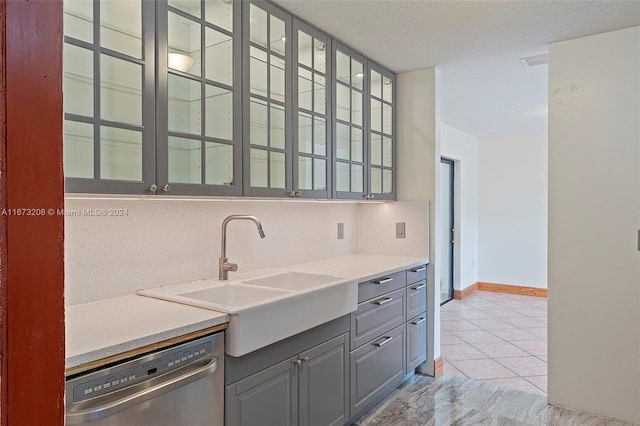 kitchen with gray cabinetry, sink, a textured ceiling, stainless steel dishwasher, and light tile patterned floors