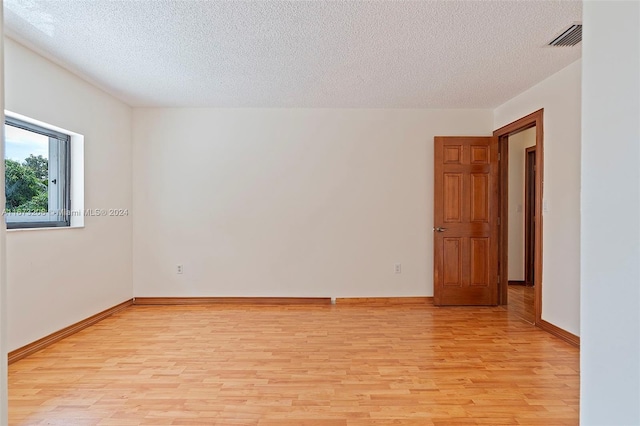 unfurnished room with a textured ceiling and light hardwood / wood-style floors