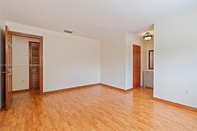 empty room featuring light hardwood / wood-style flooring and a textured ceiling