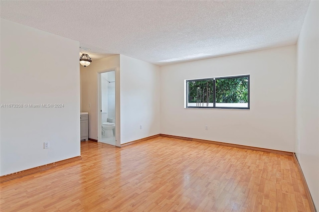 unfurnished room with light hardwood / wood-style floors and a textured ceiling