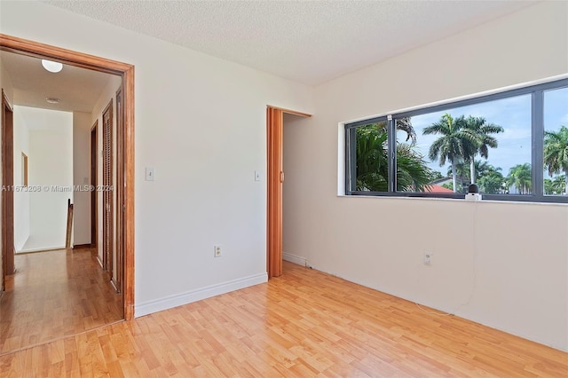 spare room featuring a textured ceiling and light wood-type flooring