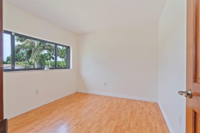 unfurnished room featuring light hardwood / wood-style floors and a textured ceiling