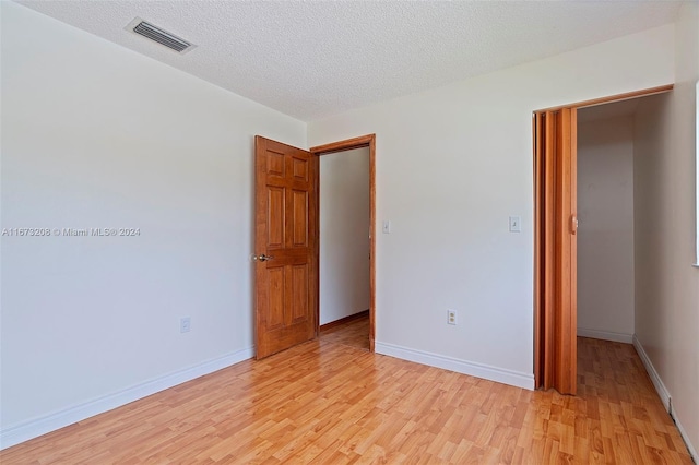 empty room with light hardwood / wood-style floors and a textured ceiling