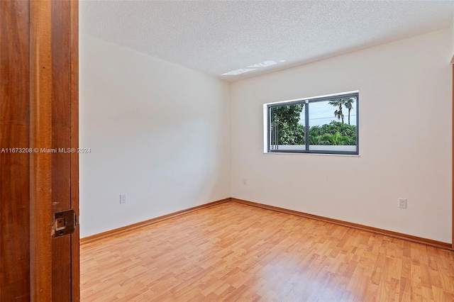 unfurnished room featuring light hardwood / wood-style flooring and a textured ceiling