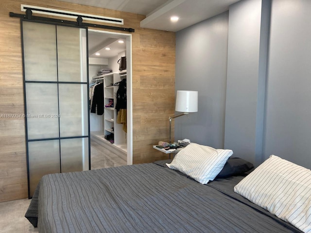 bedroom with a spacious closet, a closet, and wooden walls