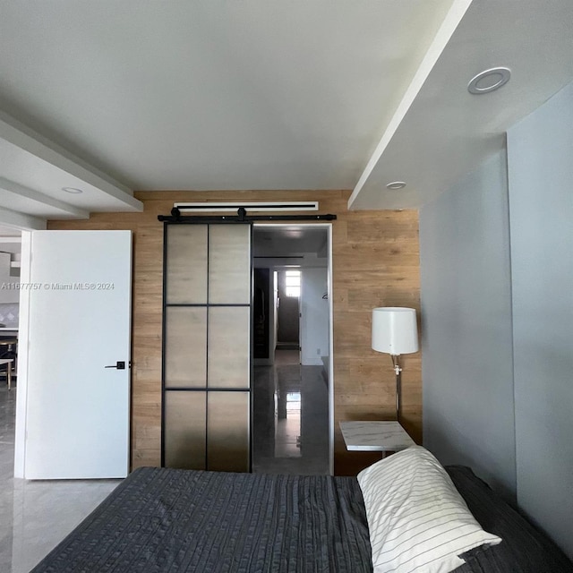 bedroom with a barn door and wood walls