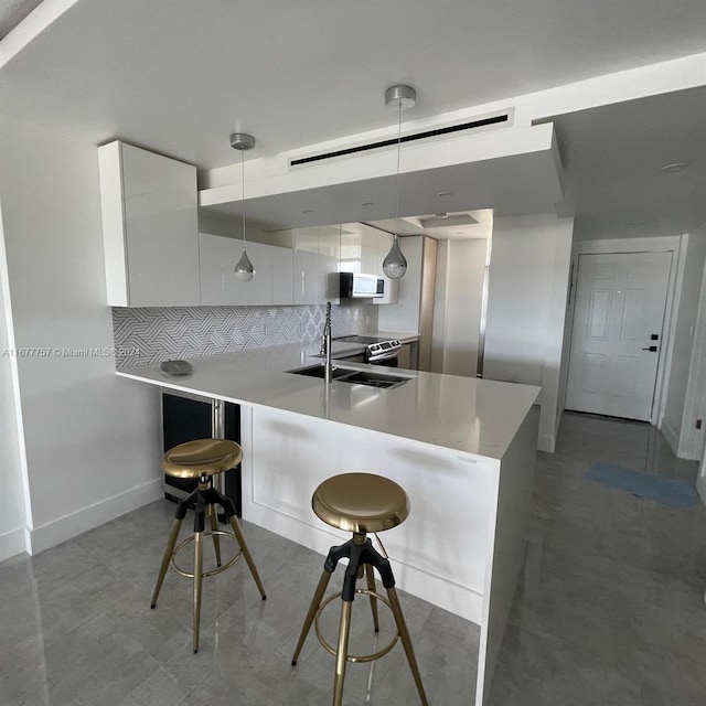 kitchen featuring a kitchen bar, kitchen peninsula, white cabinets, and hanging light fixtures