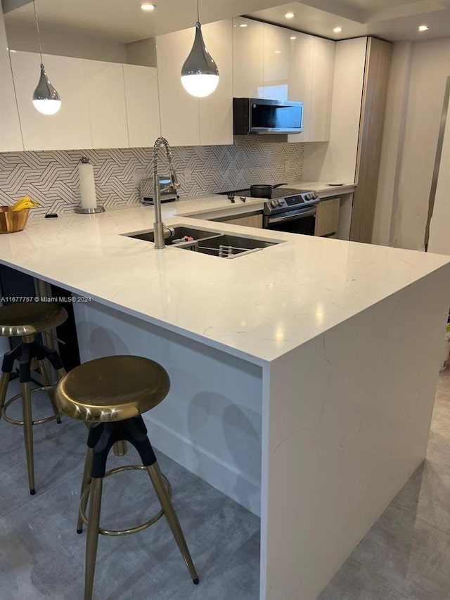 kitchen with tasteful backsplash, decorative light fixtures, white cabinets, and stainless steel appliances