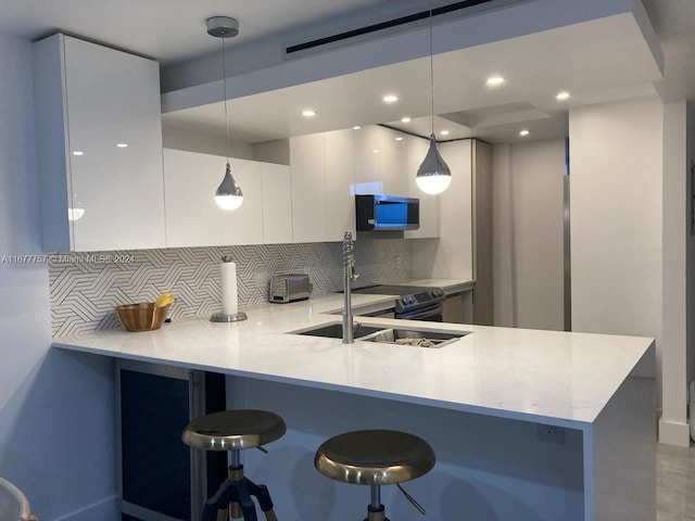 kitchen featuring pendant lighting, white cabinetry, kitchen peninsula, and tasteful backsplash