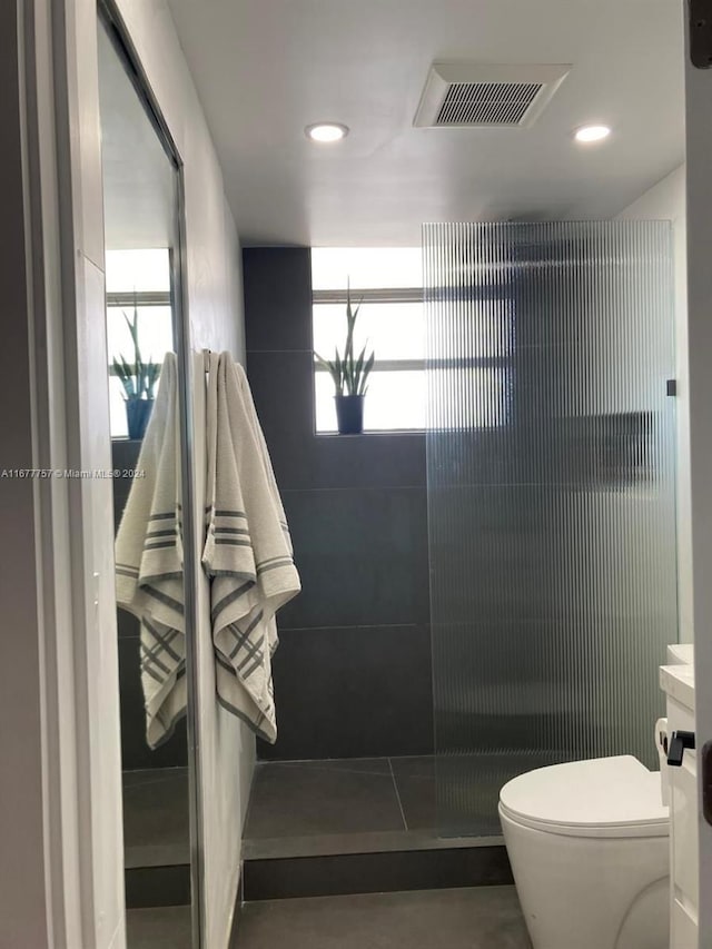 bathroom featuring vanity, toilet, a shower, and a wealth of natural light