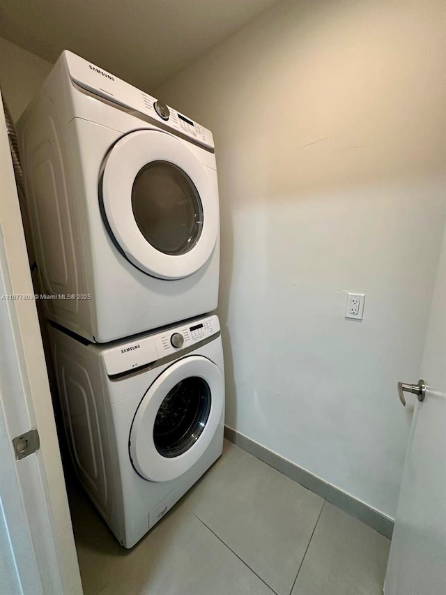 laundry area featuring stacked washing maching and dryer and light tile patterned floors