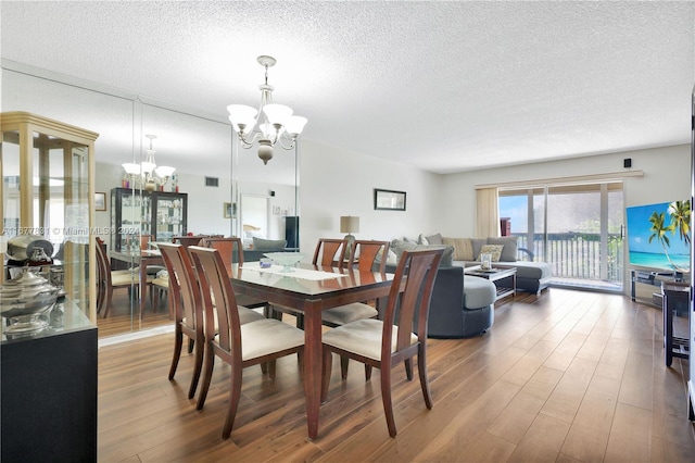 dining space featuring a notable chandelier, wood-type flooring, and a textured ceiling