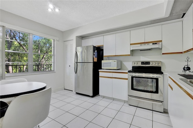 kitchen featuring a textured ceiling, white cabinets, stainless steel appliances, and light tile patterned floors