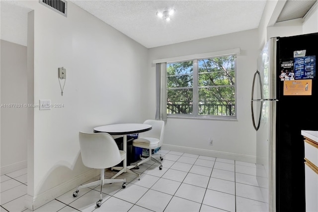 dining area featuring a textured ceiling and light tile patterned floors