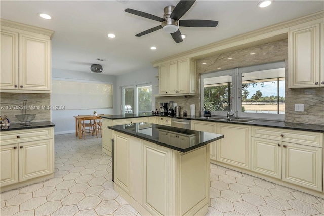 kitchen featuring ceiling fan, backsplash, stainless steel dishwasher, cream cabinetry, and sink