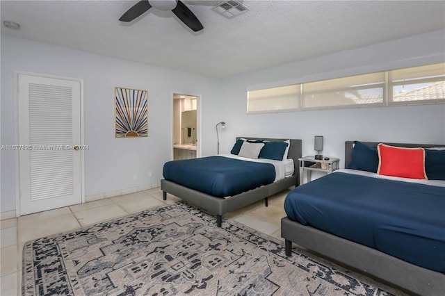 bedroom featuring a closet, light tile patterned floors, ensuite bathroom, a textured ceiling, and ceiling fan