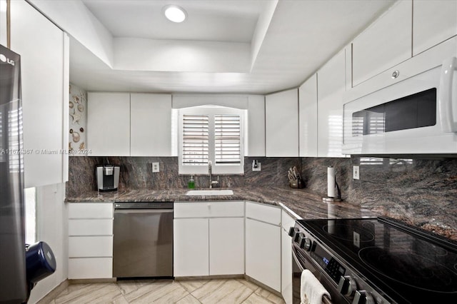 kitchen featuring sink, white cabinetry, stainless steel appliances, and dark stone counters