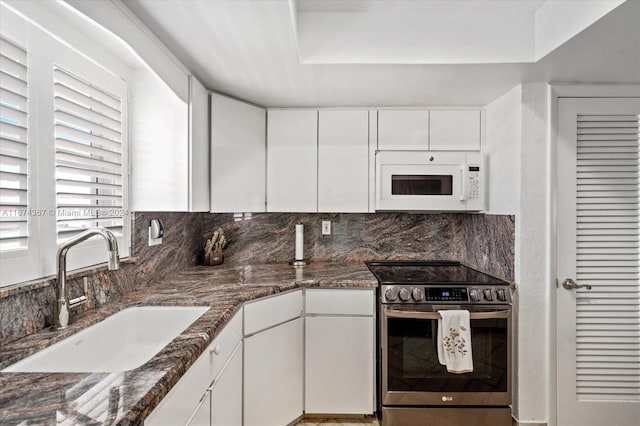 kitchen with dark stone countertops, stainless steel electric range, white cabinets, and sink