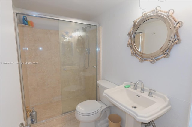 bathroom with toilet, a shower with shower door, and sink