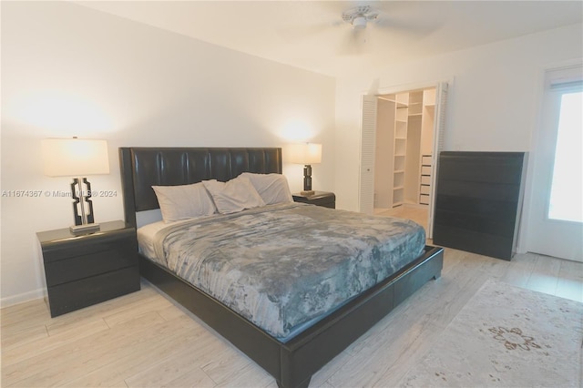 bedroom with light hardwood / wood-style flooring, a walk in closet, a closet, and ceiling fan