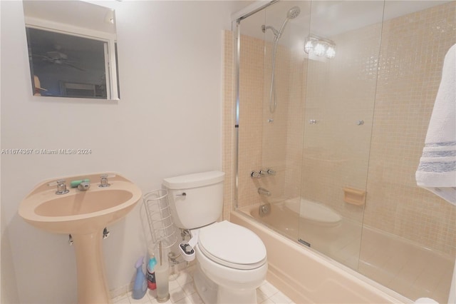 bathroom featuring toilet, bath / shower combo with glass door, and tile patterned floors