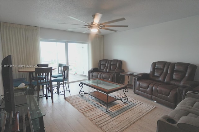 living room with light hardwood / wood-style flooring, a textured ceiling, and ceiling fan