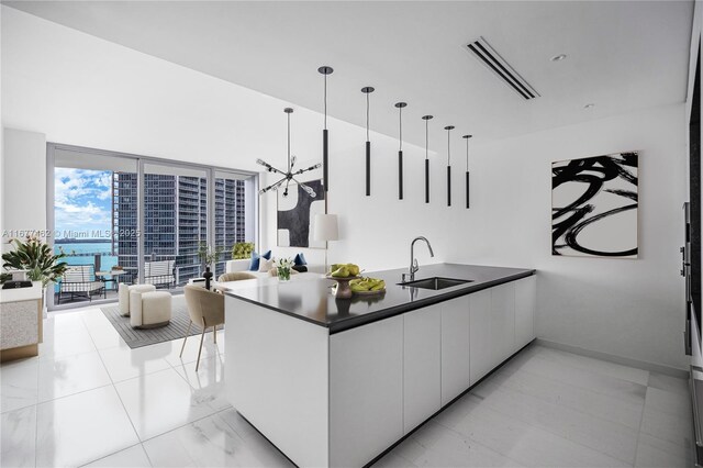 kitchen featuring floor to ceiling windows, sink, kitchen peninsula, decorative light fixtures, and white cabinets