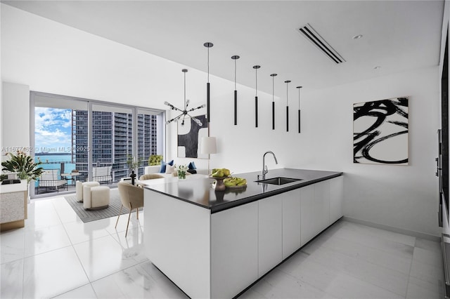 kitchen with visible vents, dark countertops, modern cabinets, white cabinetry, and a sink