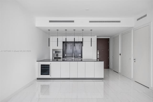 kitchen featuring refrigerator, sink, hanging light fixtures, light tile patterned flooring, and white cabinetry