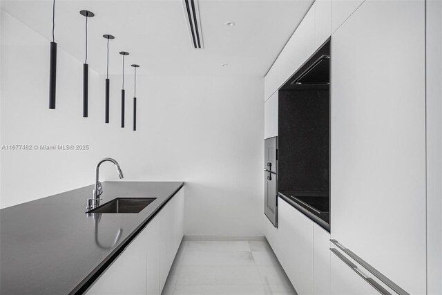 kitchen featuring pendant lighting, white cabinetry, and sink