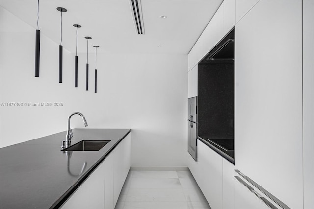 kitchen featuring a sink, white cabinetry, dark countertops, modern cabinets, and pendant lighting