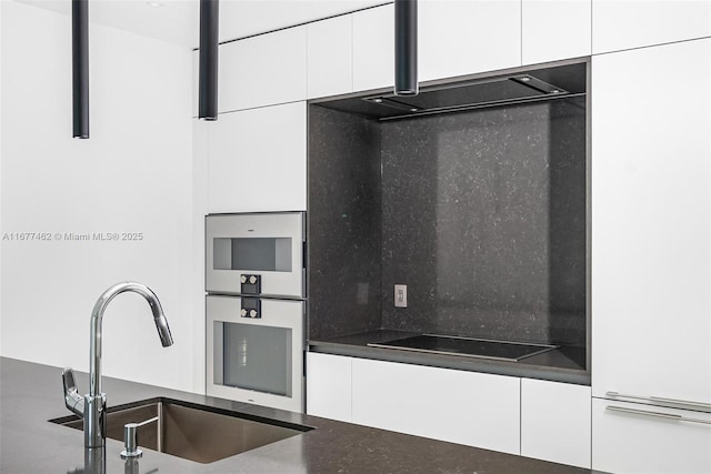 kitchen with dark countertops, white cabinetry, a sink, and black electric stovetop