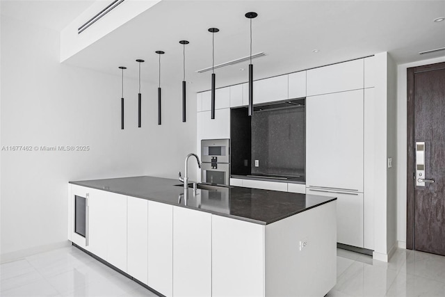 kitchen featuring a sink, white cabinets, hanging light fixtures, dark countertops, and modern cabinets