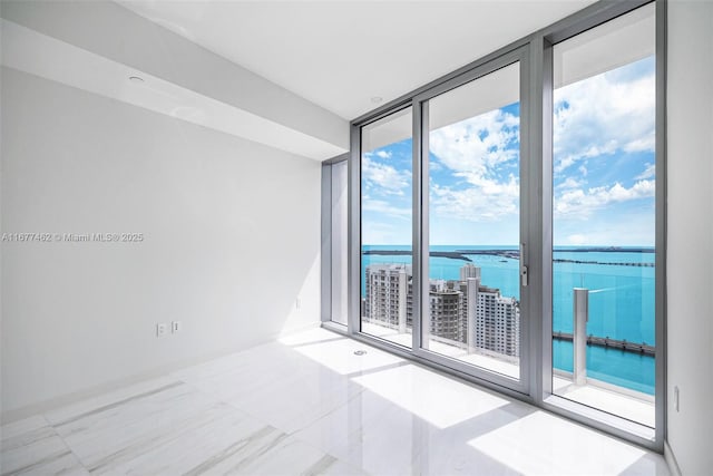 spare room featuring a wall of windows and a water view