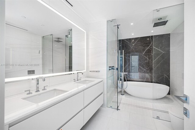 bathroom featuring tile patterned flooring, shower with separate bathtub, vanity, and tile walls