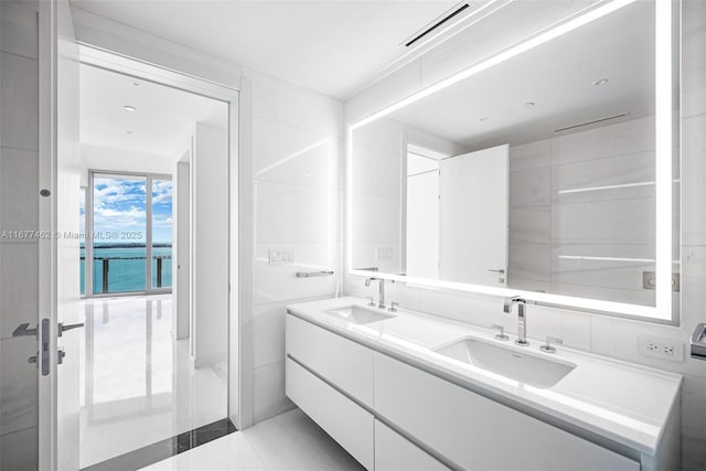 full bathroom featuring double vanity, tile walls, visible vents, and a sink