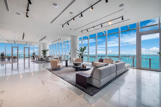 living room featuring a wall of windows, a water view, visible vents, and track lighting