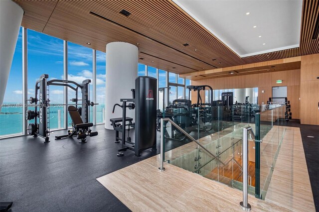 workout area with floor to ceiling windows and a water view