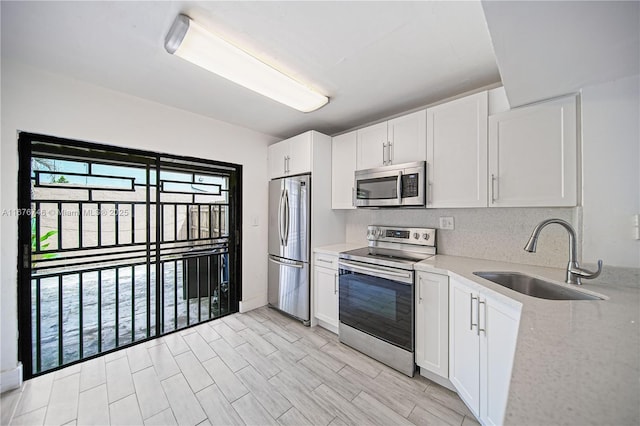 kitchen featuring white cabinetry, sink, light stone counters, and appliances with stainless steel finishes