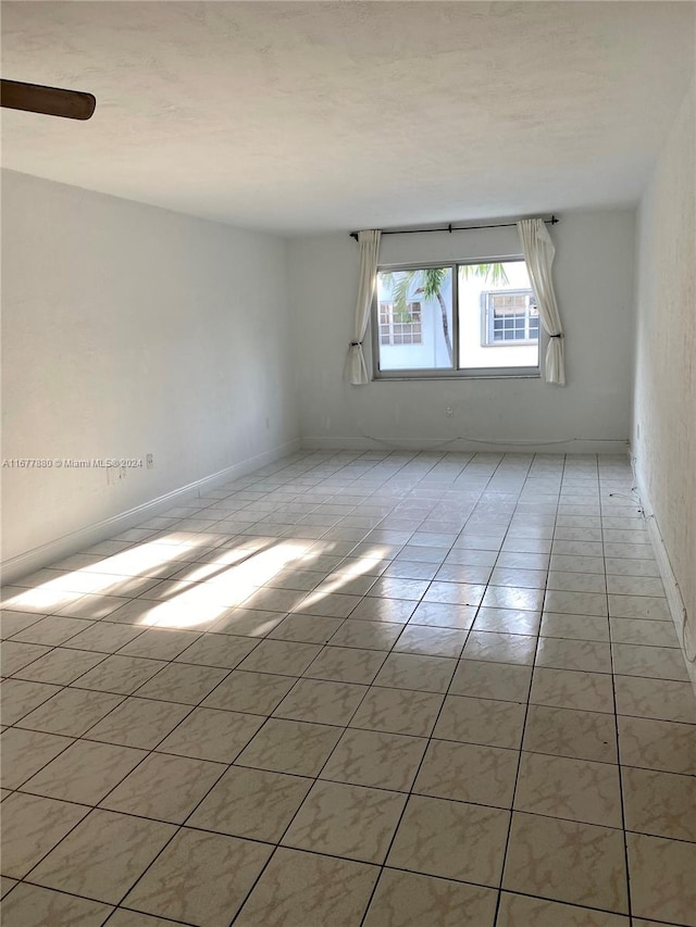 tiled spare room with ceiling fan