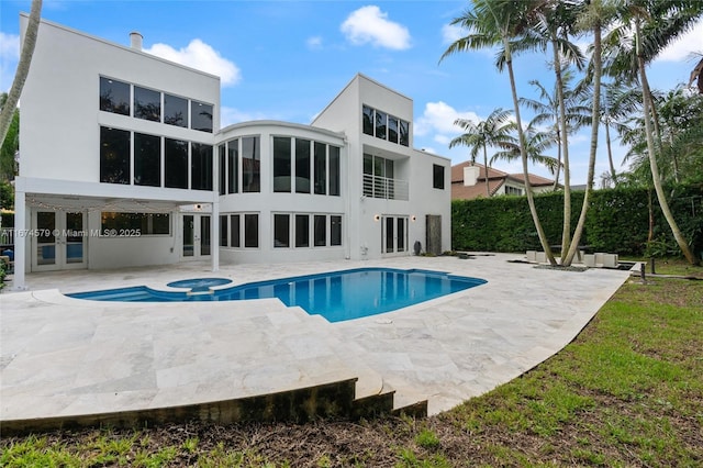 back of property with a swimming pool with hot tub and a patio