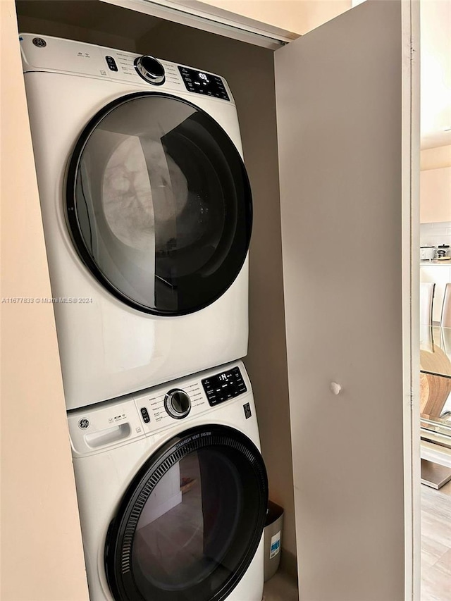 washroom featuring stacked washer / dryer and light hardwood / wood-style floors