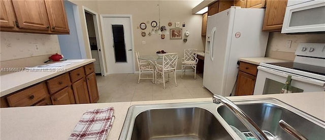 kitchen with white appliances, light tile patterned floors, and sink